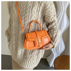 Détail du sac à bandoulière en cuir orange vif avec des finitions dorées élégantes