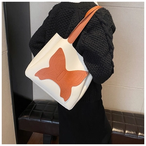 Close-up of a white tote bag featuring large orange butterfly applique and matching strap