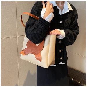 Detail of spacious beige tote bag showing large brown butterfly leather patch decoration