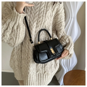 Détail du sac bandoulière en similicuir noir avec boucle ronde en métal et rabat