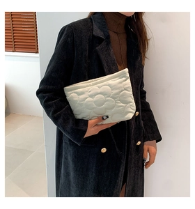 Detail van gewatteerd 3D-bloemenpatroon op een crème witte mode clutch handtas