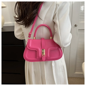 Détail du sac à bandoulière rose rouge avec ferrures dorées et design incurvé unique
