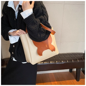 Detail of a beige and brown tote bag with a unique leather butterfly applique design