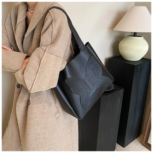 Detailed view of black faux leather tote bag with embossed butterfly pattern design