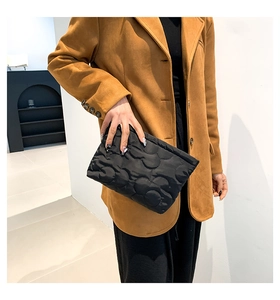 Modieuze zwarte gewatteerde cloud clutch tas vastgehouden door model tegen een achtergrond