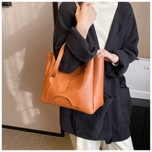 Close-up of caramel tote bag with butterfly stitching detail on a model shoulder