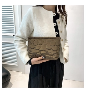 Bruine gewatteerde clutch met bloemenpatroon en metalen rits in de hand van een model