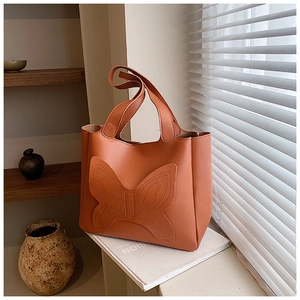 Close-up of butterfly quilted stitching on brick orange matte leather tote bag