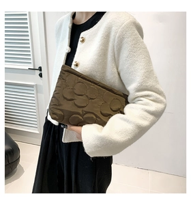 Detailweergave van een bruine gewatteerde clutch met bloemmotieven en zachte katoenstructuur