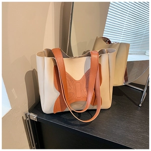Detail of cream tote bag featuring orange butterfly stitching on textured faux leather