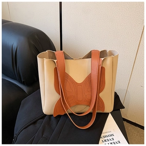 Detail of off-white tote bag featuring orange butterfly patch and refined stitching