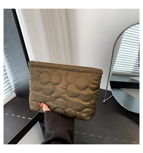 Detail van olijfgroene gewatteerde clutch met bloemmotieven en een gouden ritssluiting