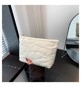 Detail van een crème gewatteerde clutch met bloemstiksel en gouden ritssluiting