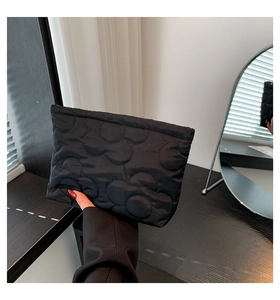 Detailopname van zwarte doorgestikte bloemenclutch vastgehouden in een interieur