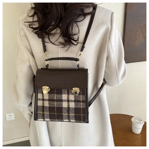 Detail of vintage plaid mini backpack featuring brown leather trim and golden buckle
