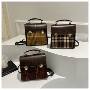 Three retro plaid handbags with leather flaps on a minimalist display stand