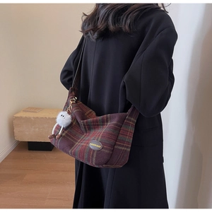 Retro plaid hobo bag with plush monster charm worn by model for commuting look