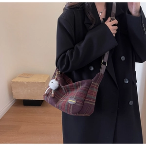 Detail of vintage plaid shoulder bag featuring a fuzzy white charm and leather strap