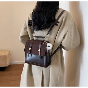 Close-up of vintage brown PU leather backpack with gold buckles and plush charm on side