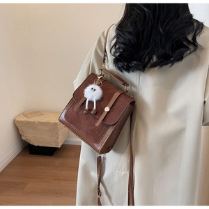 Detail of dark brown vintage backpack with leather texture and plush monster charm