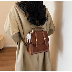 Model view of a vintage dark brown matte patchwork backpack with a plush charm accessory