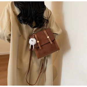 Detail of vintage brown patchwork handbag with suede texture and plush doll charm