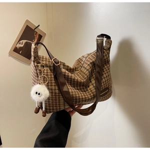 Detail of vintage brown plaid shoulder bag with plush charm and fashion brand label