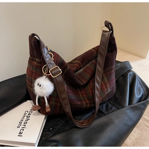 Detail of vintage plaid shoulder bag with leather strap and plush monster charm