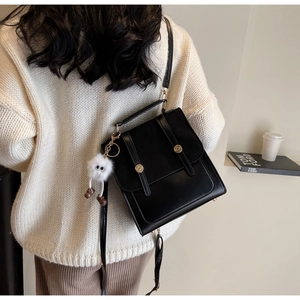 Detail of vintage black matte leather backpack with gold buckles and plush charm