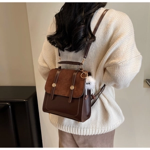 Retro patchwork brown matte backpack shown on model with fuzzy monster charm