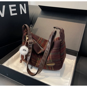 Detail of vintage plaid wool shoulder bag with plush eye charm in premium gift box