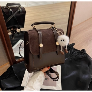 Detail of vintage brown leather bag with suede flap and cute white monster plush charm