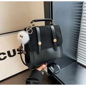 Detail of vintage black backpack with decorative straps and white plush monster charm