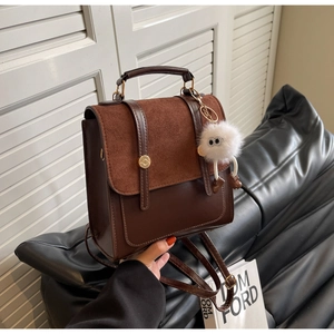 Detail of vintage color-block backpack with metal handle and cute plush monster charm