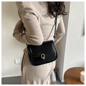 Détail d'un sac besace en cuir noir avec boucle dorée et fine bandoulière réglable