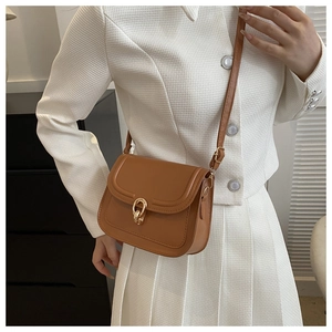 Détail du sac à bandoulière marron caramel avec fermoir doré porté par un modèle