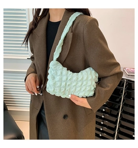 Detail of light green ruched texture fabric on a stylish underarm dumpling bag