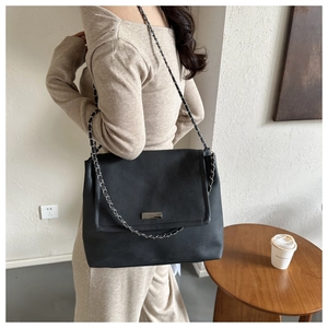 Détail du sac cabas en cuir noir avec boucle argentée et bandoulière en chaîne