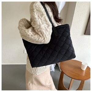 Detailed view of black quilted tote bag with diamond stitching and slim shoulder strap