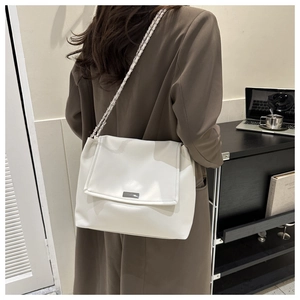 Détail du sac à bandoulière en cuir blanc avec plaque logo argentée et chaîne