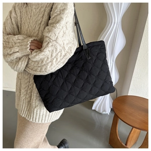 Detailed view of the black quilted texture and stitching on the large tote shoulder bag