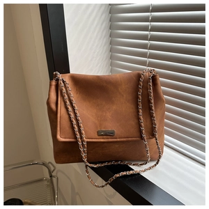 Détail d'un sac bandoulière marron caramel avec chaîne argentée et texture mate élégante