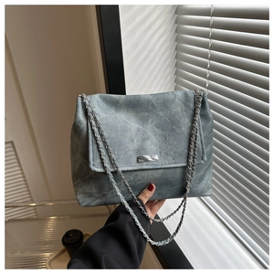 Détail d'un sac à bandoulière gris délavé avec plaque argentée et bandoulières en chaîne