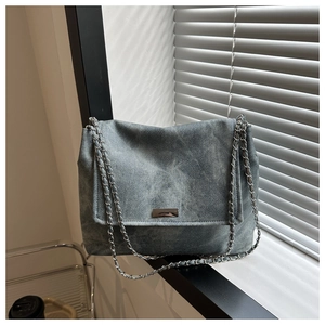 Détail du sac à bandoulière en denim délavé avec boucle argentée et bandoulière chaîne
