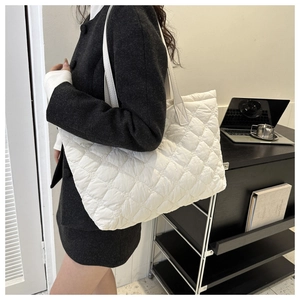 Close-up of white quilted tote bag featuring a diamond stitch and padded nylon texture