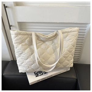 Detail of white quilted tote bag with soft texture and long shoulder straps