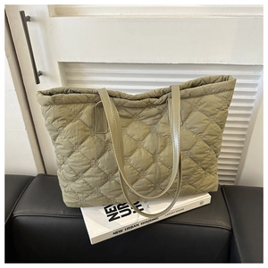 Detailed view of sage green quilted tote bag with rhombus stitching and leather handles