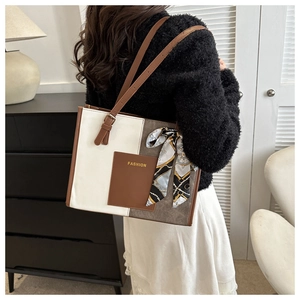 Detail view of contrast color patchwork tote bag with fashion tag and silk scarf handle decor