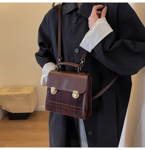 Detail of vintage contrast briefcase showing green plaid fabric and gold lock