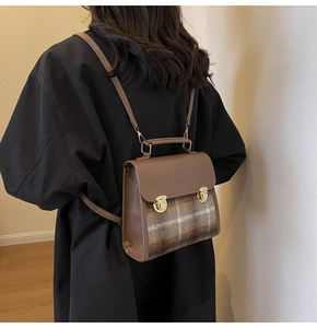Detail of vintage plaid briefcase backpack with brown leather trim and gold metal locks